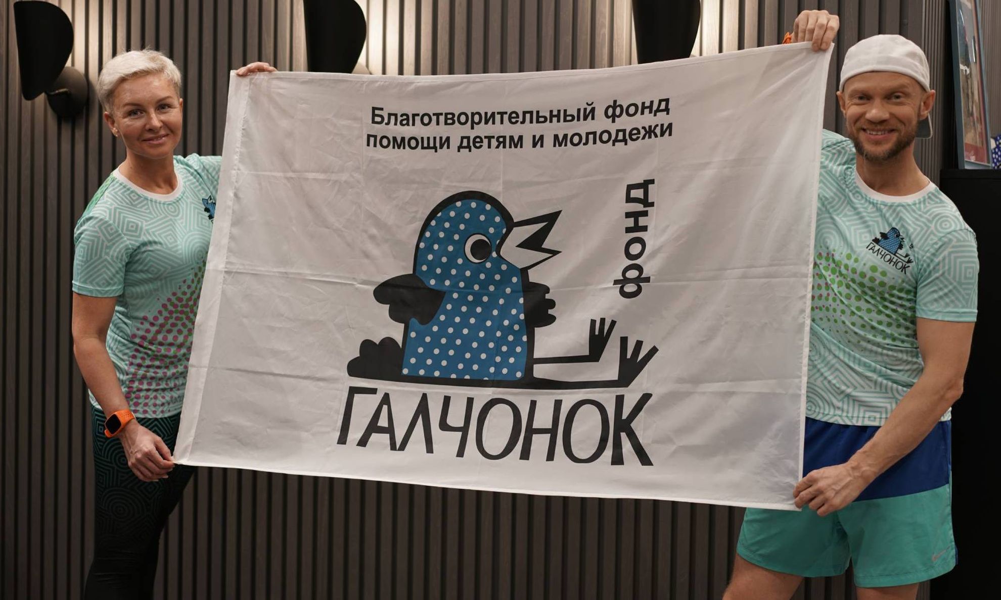 Татьяна и Дмитрий Хрусталев держат флаг Фонда "ГАЛЧОНОК"