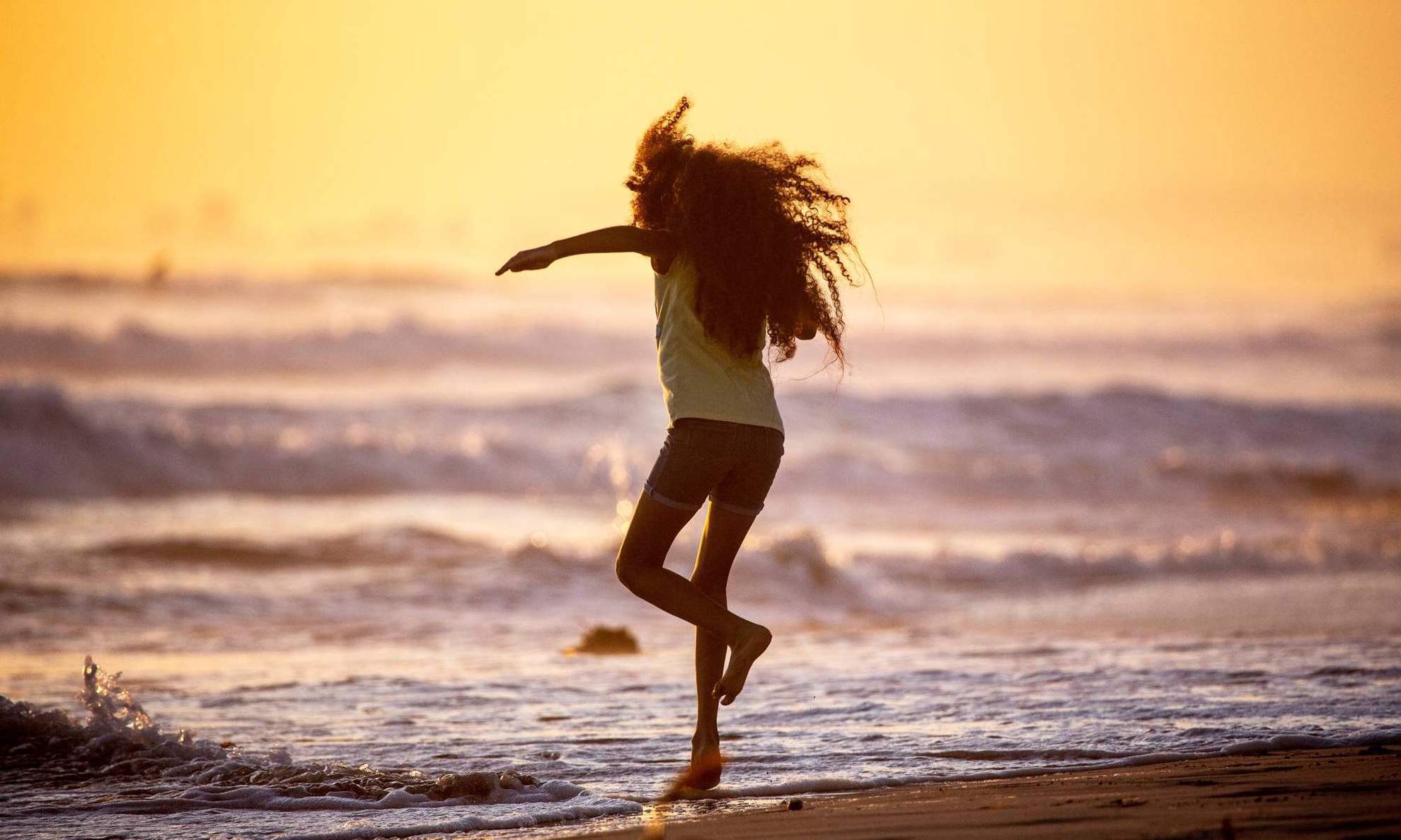 Девочка бежит по пляжу на закате