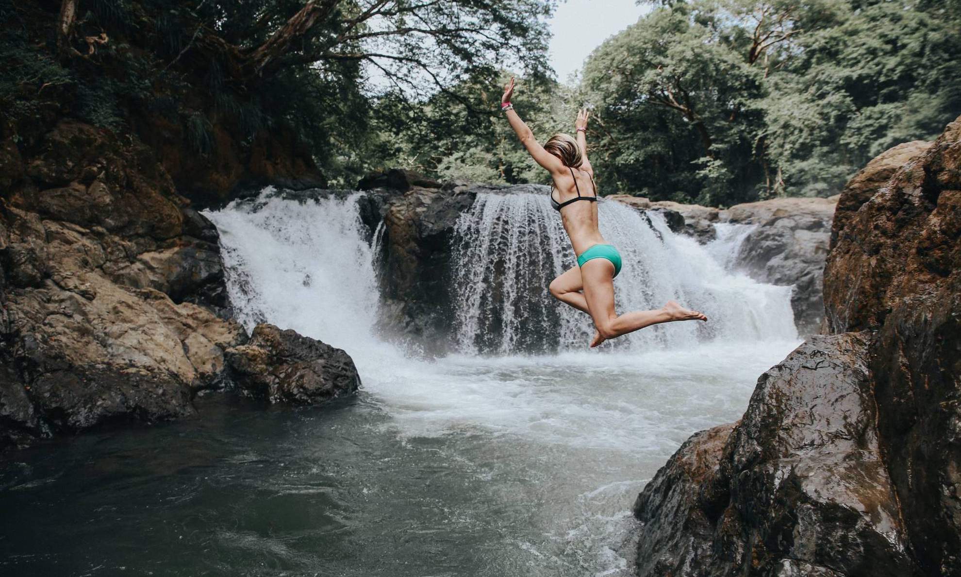 Девушка прыгает в воду в горах Коста-Рики
