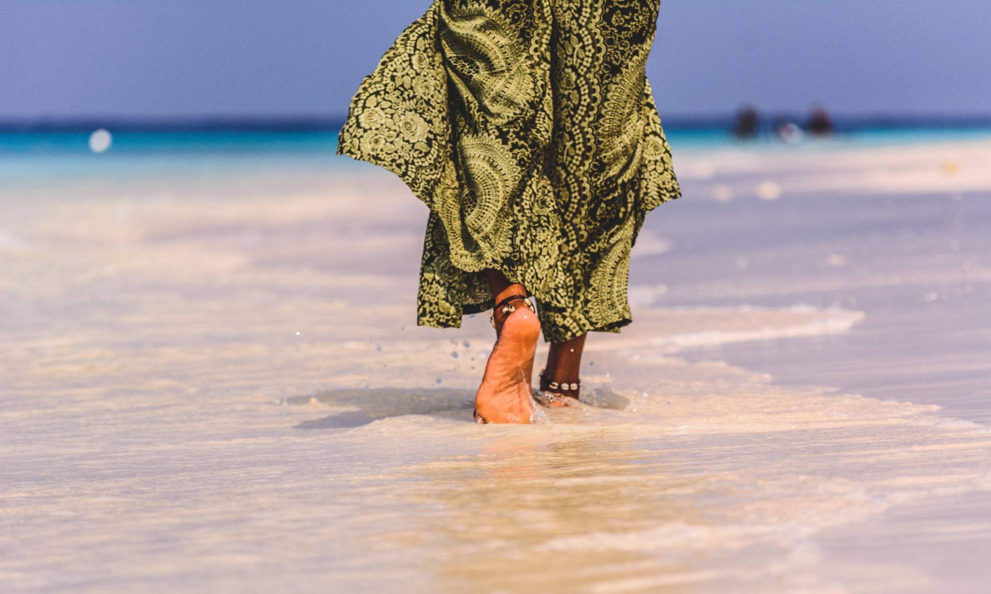 Девушка в национальной одежде гуляет по пляжу