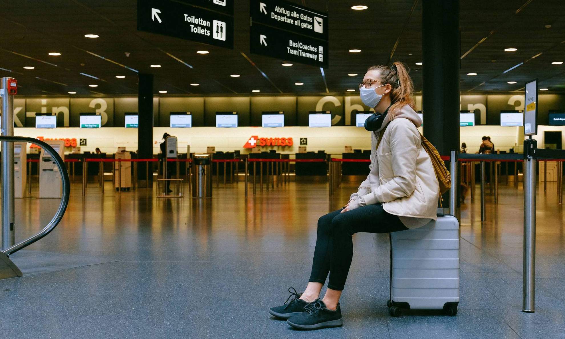 Девушка сидит на чемодане в зале ожидания