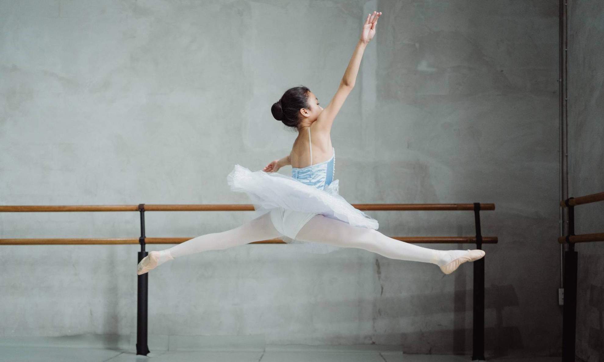 Девочка в балетной пачке прыгает в шпагат