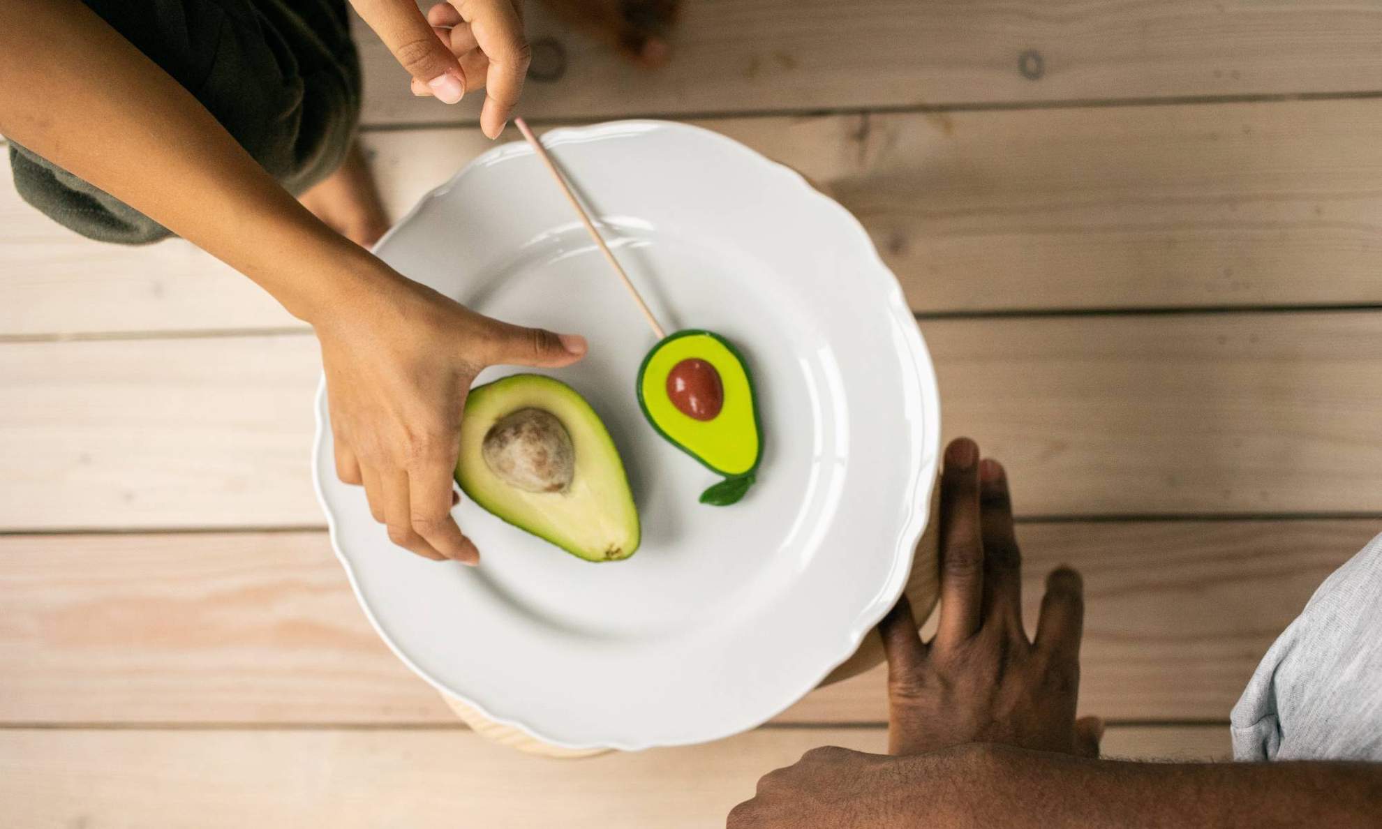 К авокадо на тарелке тянутся руки