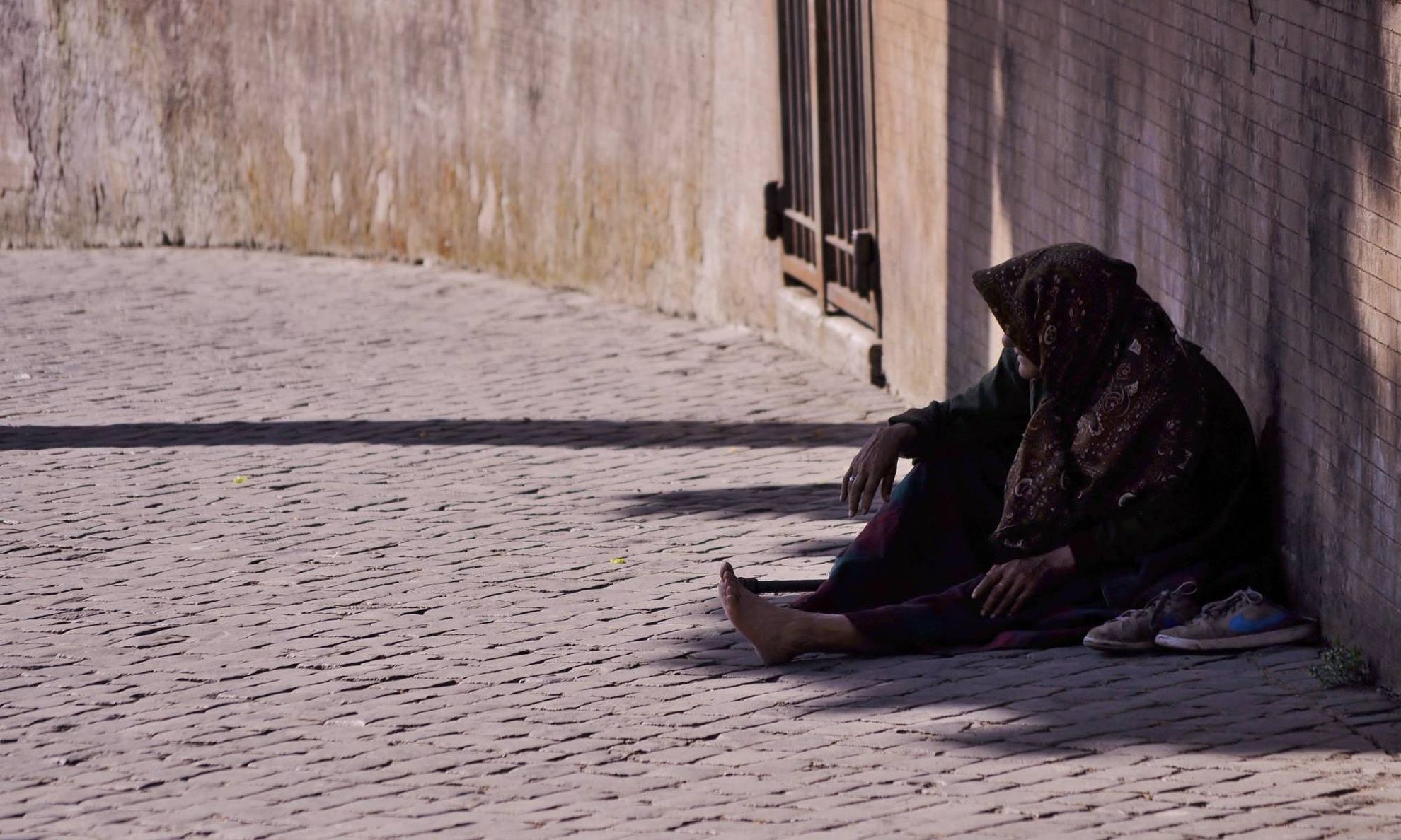 Бездомная пожилая женщина в платке на улице