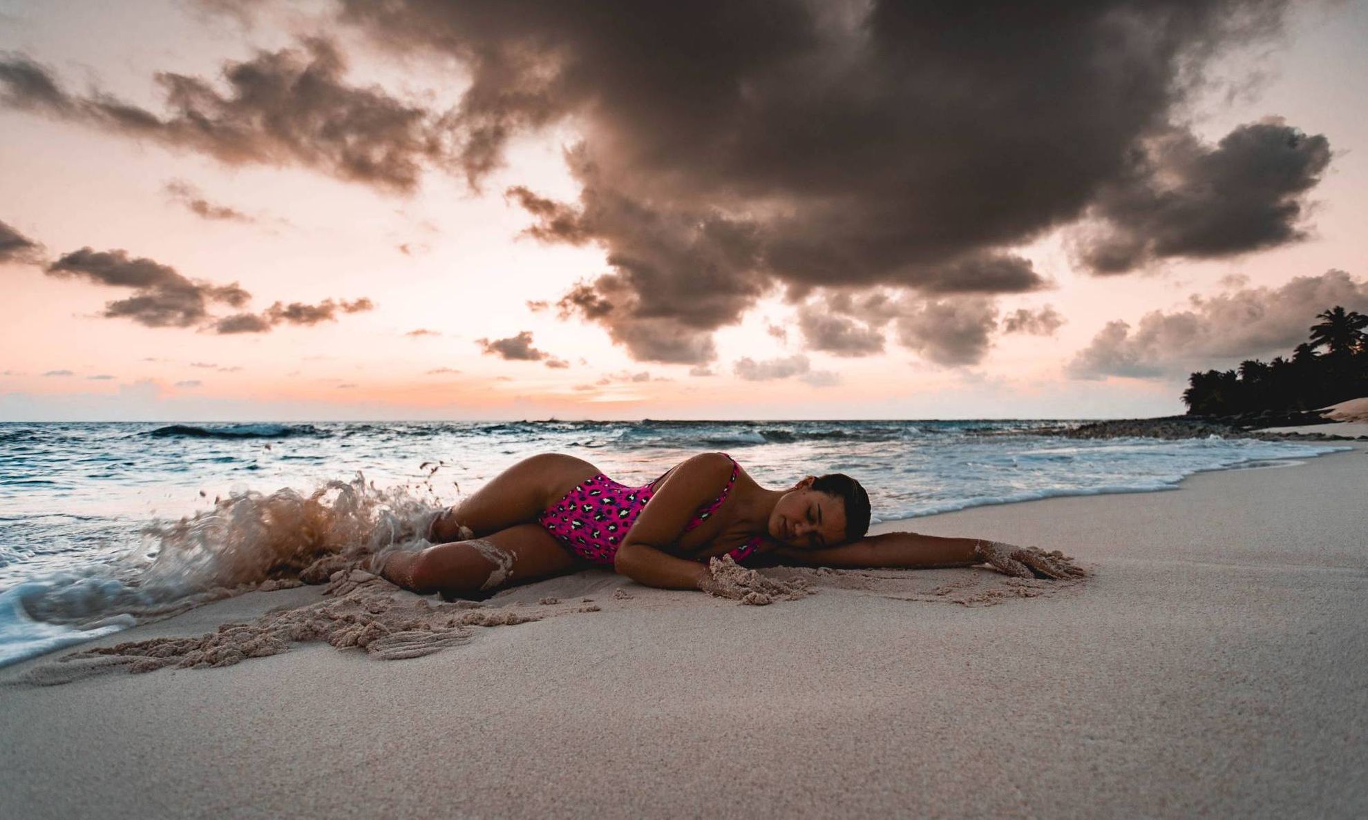 Девушка в купальнике лежит на пляже